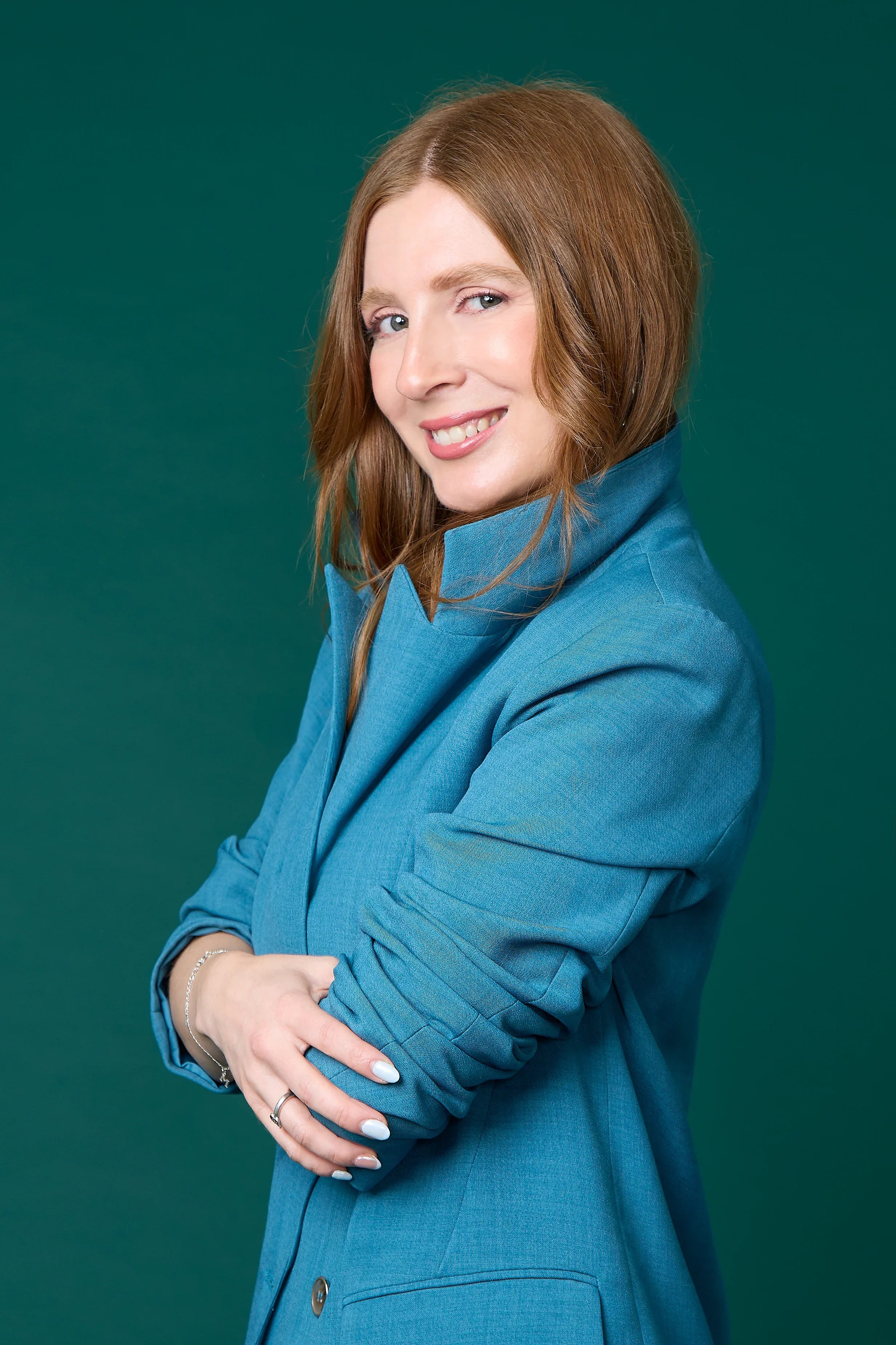 mujer sonriente con cabello castaño, saco azul y fondo verde, asesoría de imagen