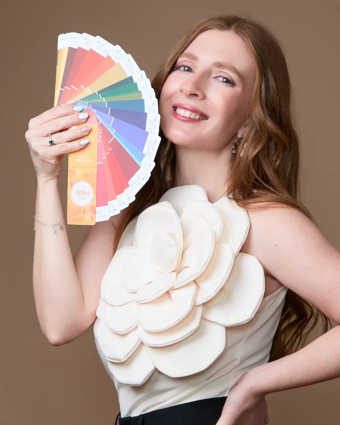 Mujer sonriente con carta de colores, asesoría de imagen y análisis de color personal.